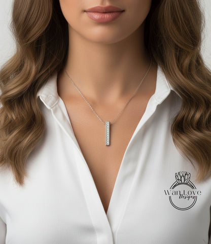 A close-up of a woman's neck and chest wearing a white blouse with a necklace featuring a pendant.