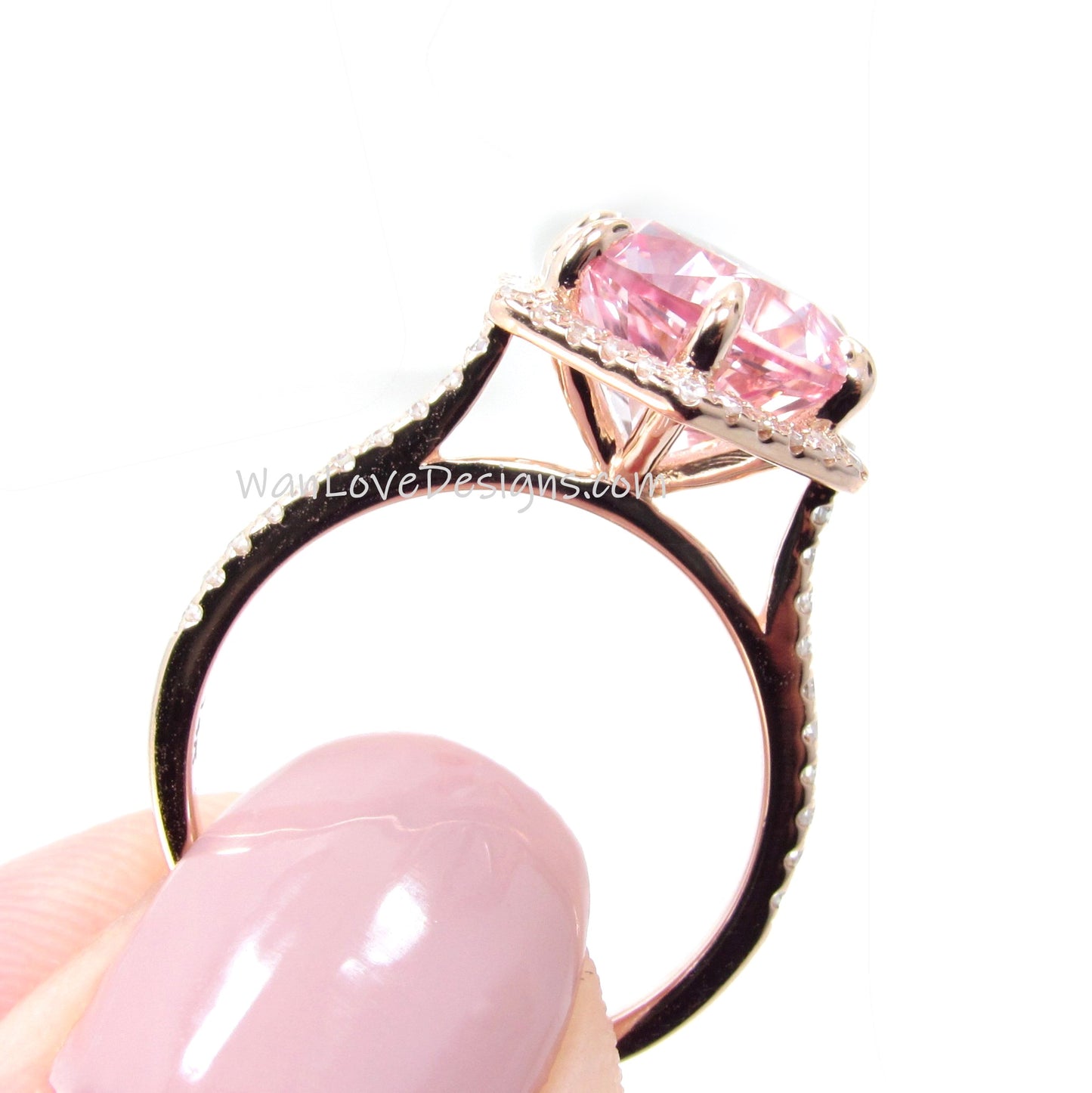 a woman holding a pink diamond ring in her hand