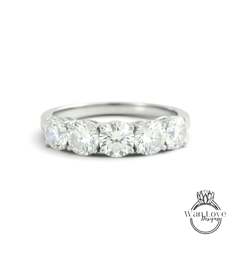 A silver ring with a row of five large, clear diamonds set in the band.