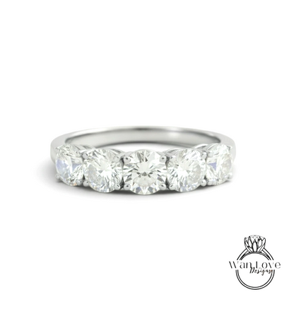 A silver ring with a row of five large, clear diamonds set in the band.