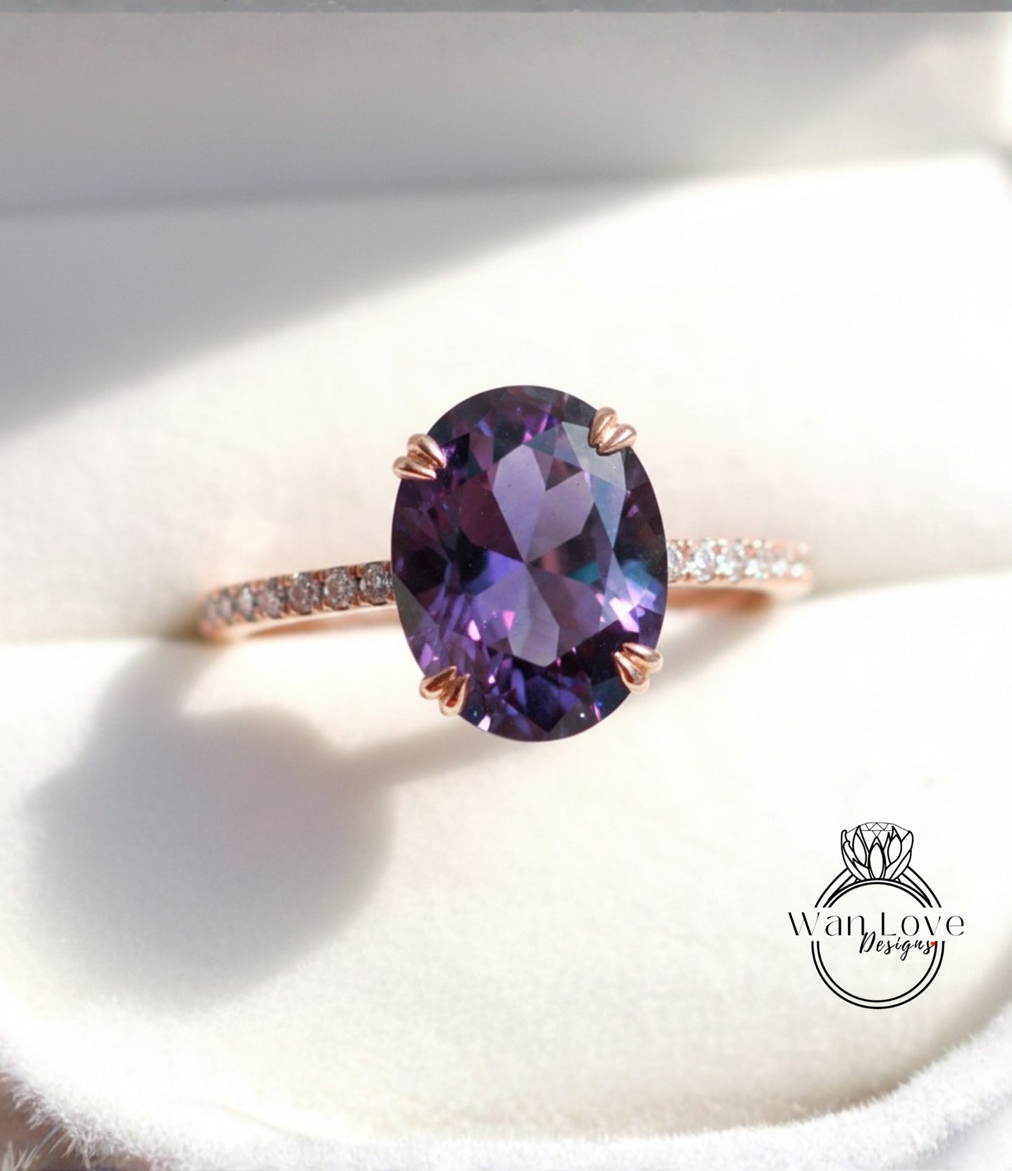 A close-up image of a ring with a large oval-shaped purple gemstone, likely an amethyst, set in a rose gold band.