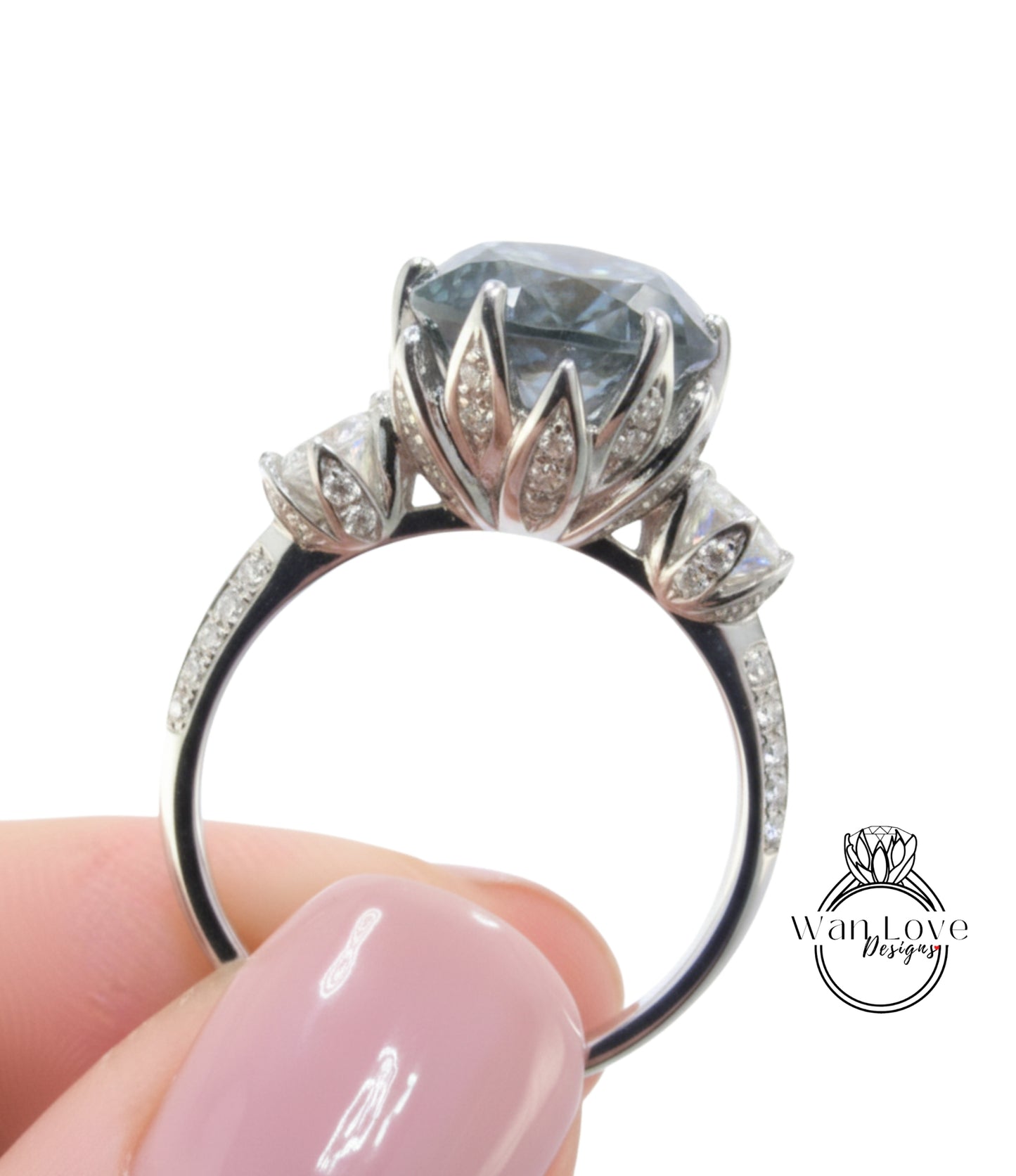 A close-up of a person's hand holding a silver ring with a large, blue gemstone.