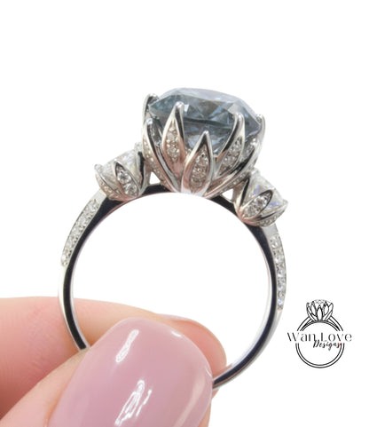 A close-up of a person's hand holding a silver ring with a large, blue gemstone.