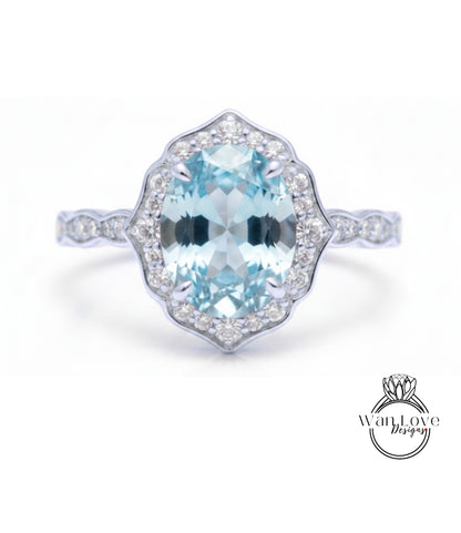 A stunning light blue gemstone ring with a halo of smaller diamonds around the center stone.