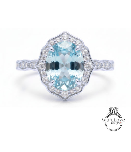 A stunning light blue gemstone ring with a halo of smaller diamonds around the center stone.