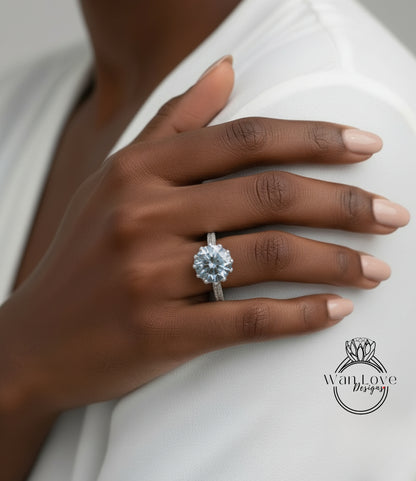 A close-up of a person's hand wearing a large diamond ring on the ring finger.