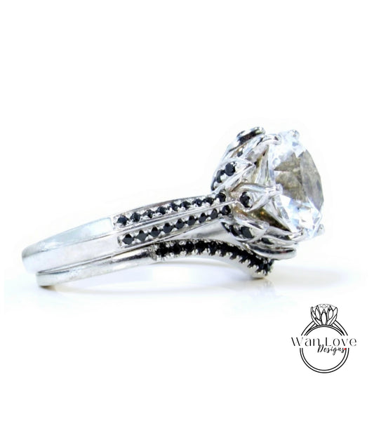A silver ring with a large, clear gemstone, likely a diamond, set in a decorative band with black accents.