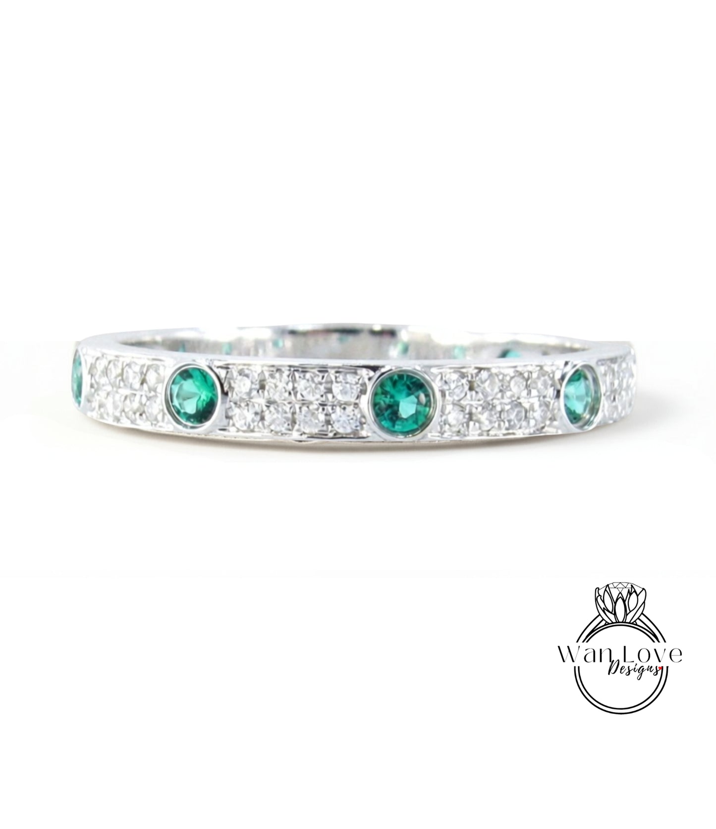 A silver band adorned with green gemstones, including diamonds, and a logo for "WanLove Designs".