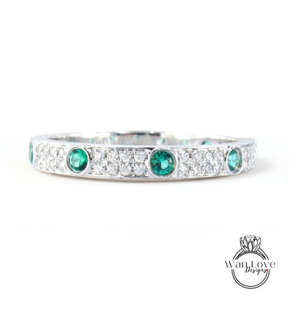 A silver band adorned with green gemstones, including diamonds, and a logo for "WanLove Designs".