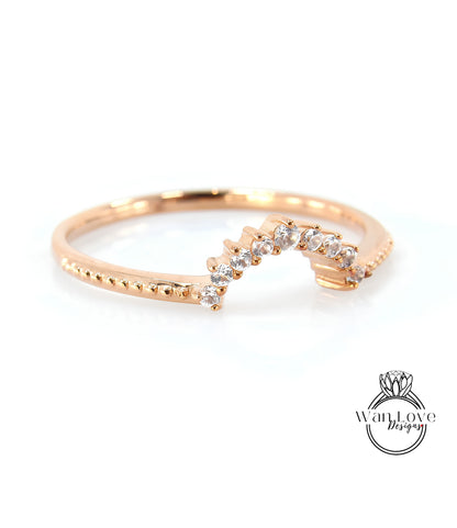A gold ring with a diamond-encrusted band, featuring a curved design with a row of small diamonds along the band.