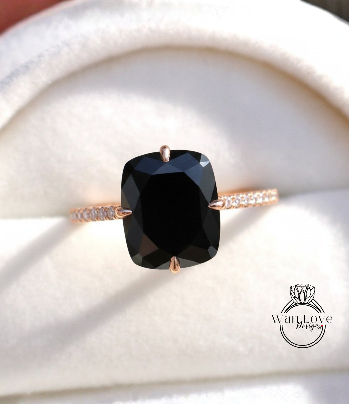 A close-up image of a gold ring with a large black diamond as the centerpiece, placed on a white background.