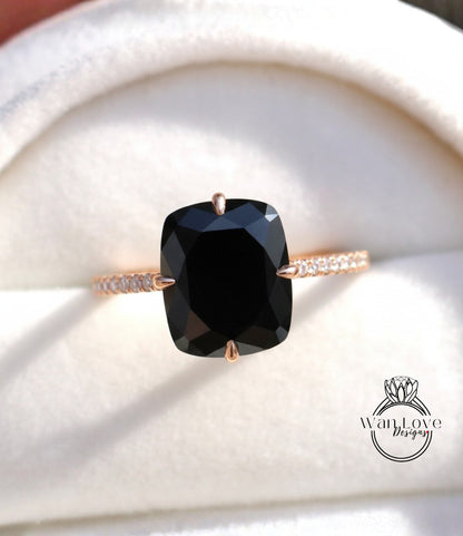 A close-up image of a gold ring with a large black diamond as the centerpiece, placed on a white background.