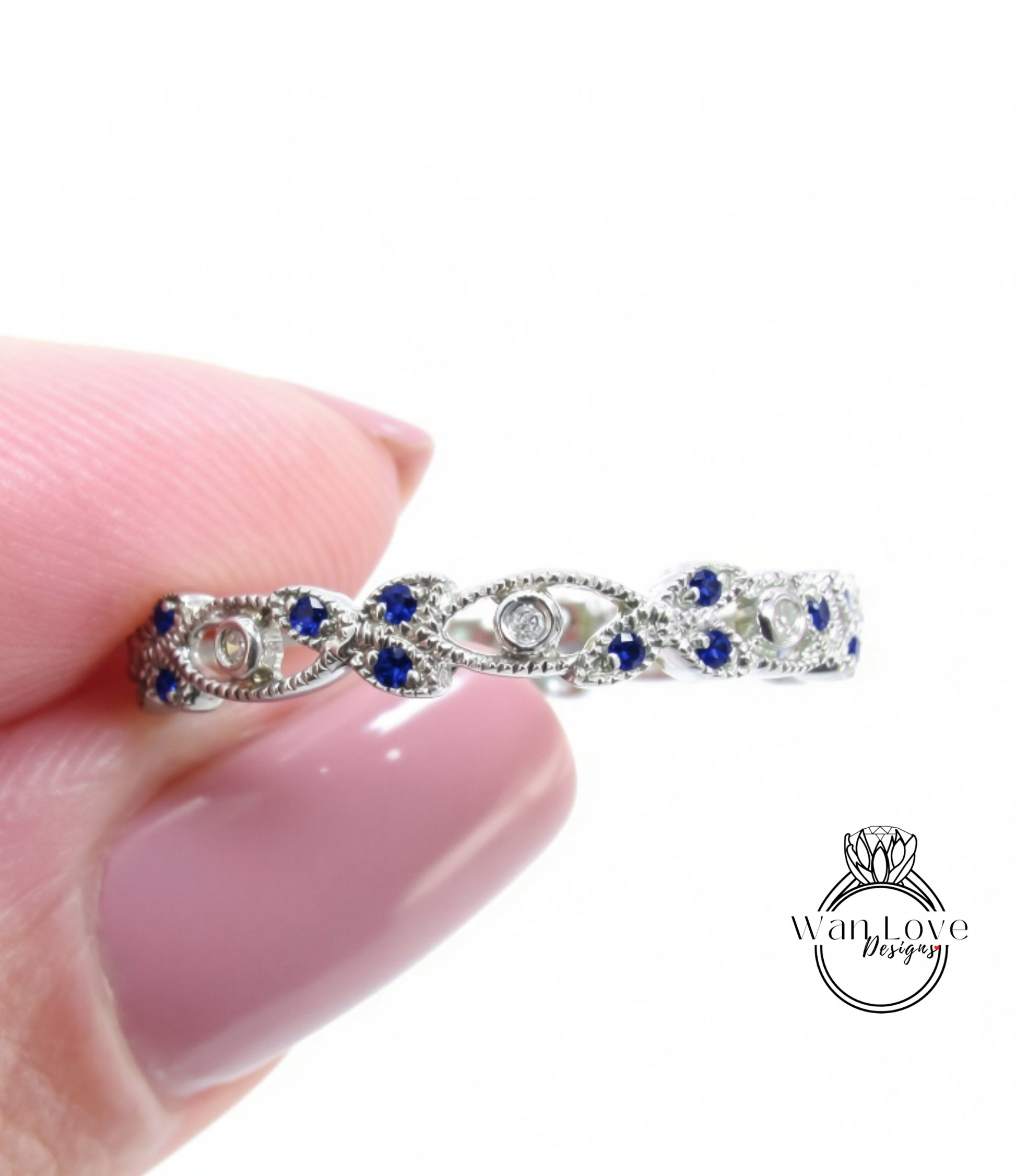 A close-up image of a person's hand holding a silver ring adorned with blue gemstones.