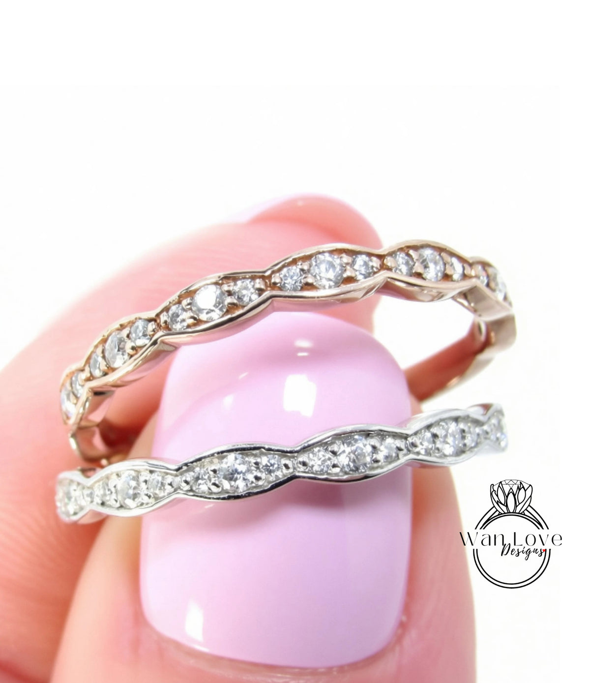 A close-up of a person's hand holding a ring with a pink background.