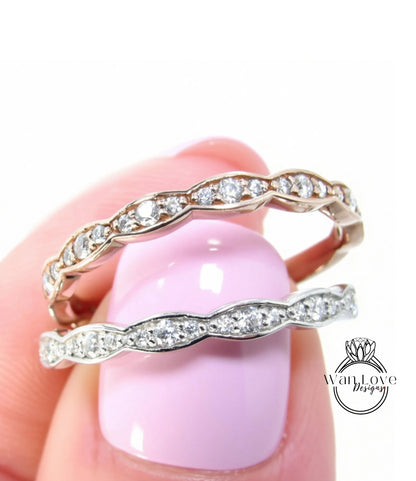 A close-up of a person's hand holding a ring with a pink background.