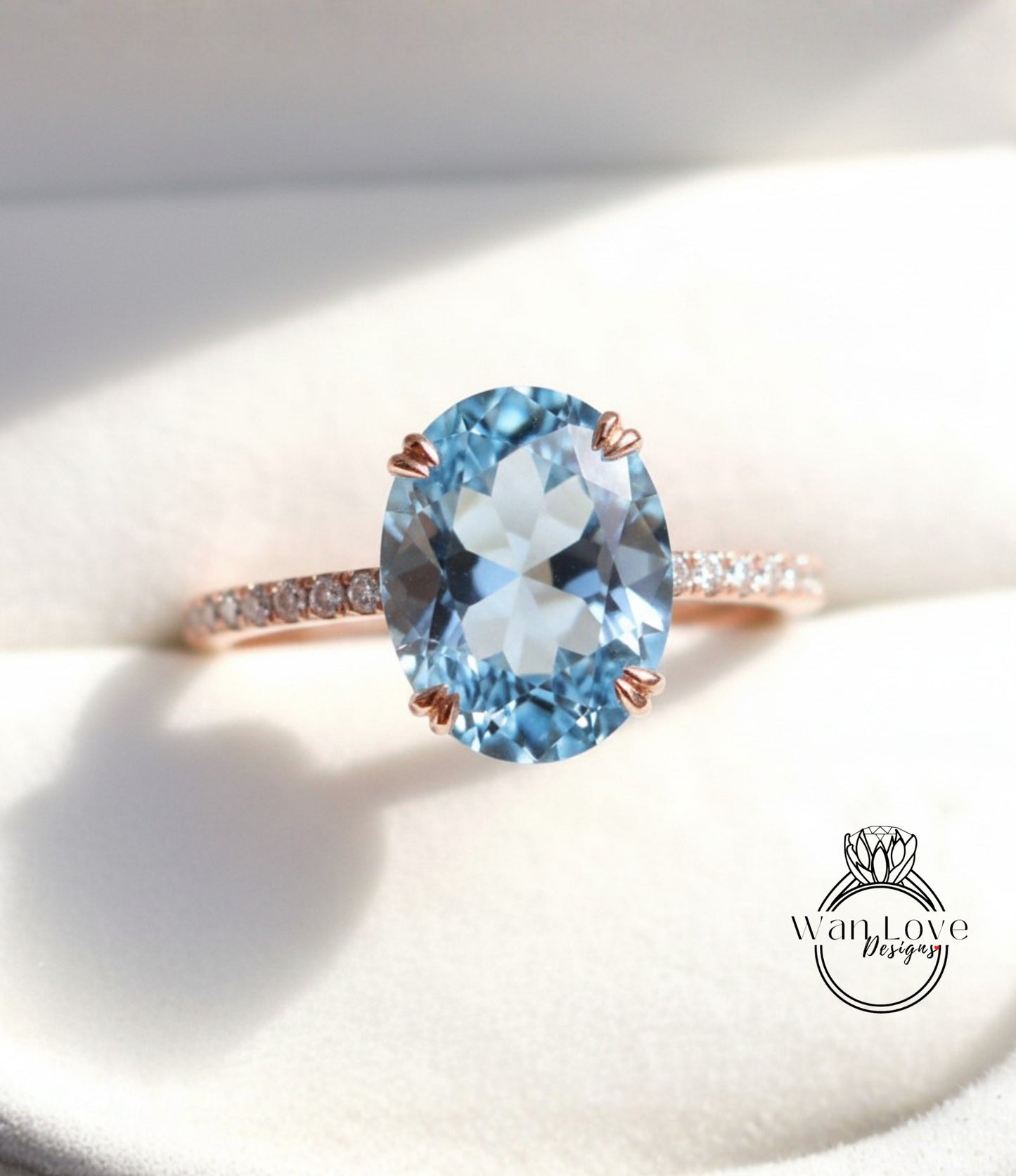 A close-up image of a rose gold ring with a large oval-shaped blue gemstone, possibly a blue topaz, set in the center of the band.