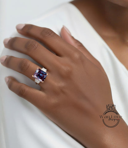 A close-up of a hand wearing a large, square-cut purple gemstone ring on the ring finger.