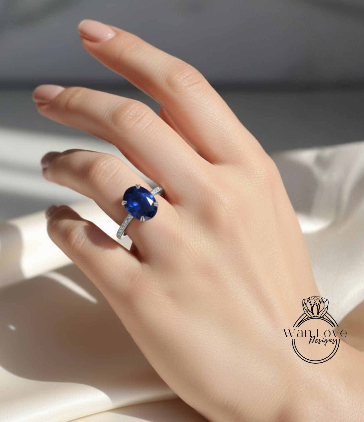 A close-up of a hand wearing a ring with a large blue gemstone, likely a sapphire, on the ring finger.
