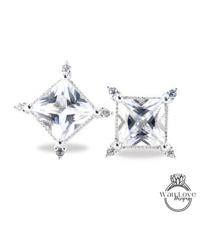 two diamond-encrusted earrings with large, clear gemstones set in a square-shaped design.