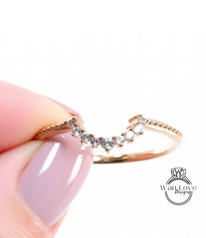 A close-up image of a person's hand holding a gold ring with a diamond-encrusted band.
