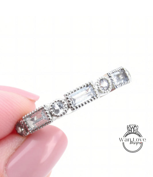 A close-up image of a person's hand holding a silver ring adorned with small, clear gemstones.