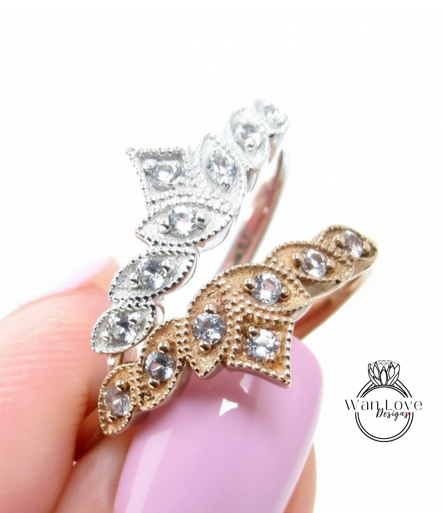 A close-up of a hand holding a ring with a decorative leaf design and clear gemstones.