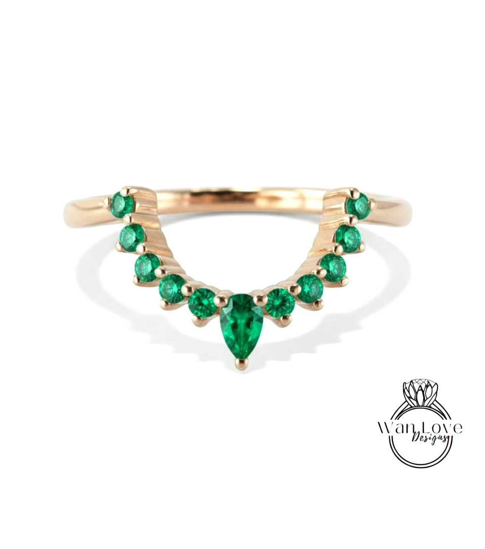 A gold ring with a large central green gemstone surrounded by smaller green gemstones arranged in a decorative pattern.