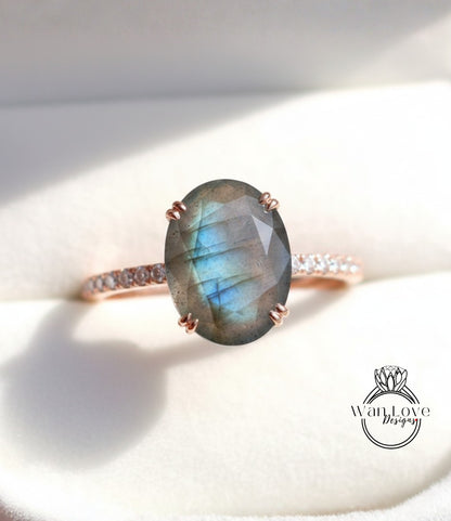 A close-up image of a rose gold ring with a large oval-shaped blue gemstone, possibly a diamond, set in the center of the band.