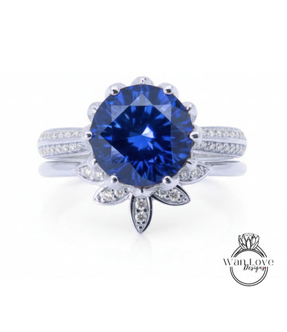 A stunning blue gemstone ring with a large central diamond surrounded by smaller diamonds, set in a silver band with a leaf-shaped accent.