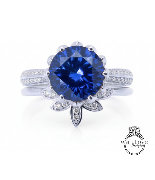 A stunning blue gemstone ring with a large central diamond surrounded by smaller diamonds, set in a silver band with a leaf-shaped accent.