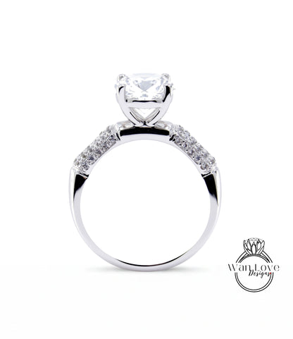 A close-up view of a silver engagement ring with a large central diamond and smaller diamonds on either side.