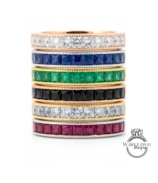 A stack of rings with various colored gemstones set in gold bands.