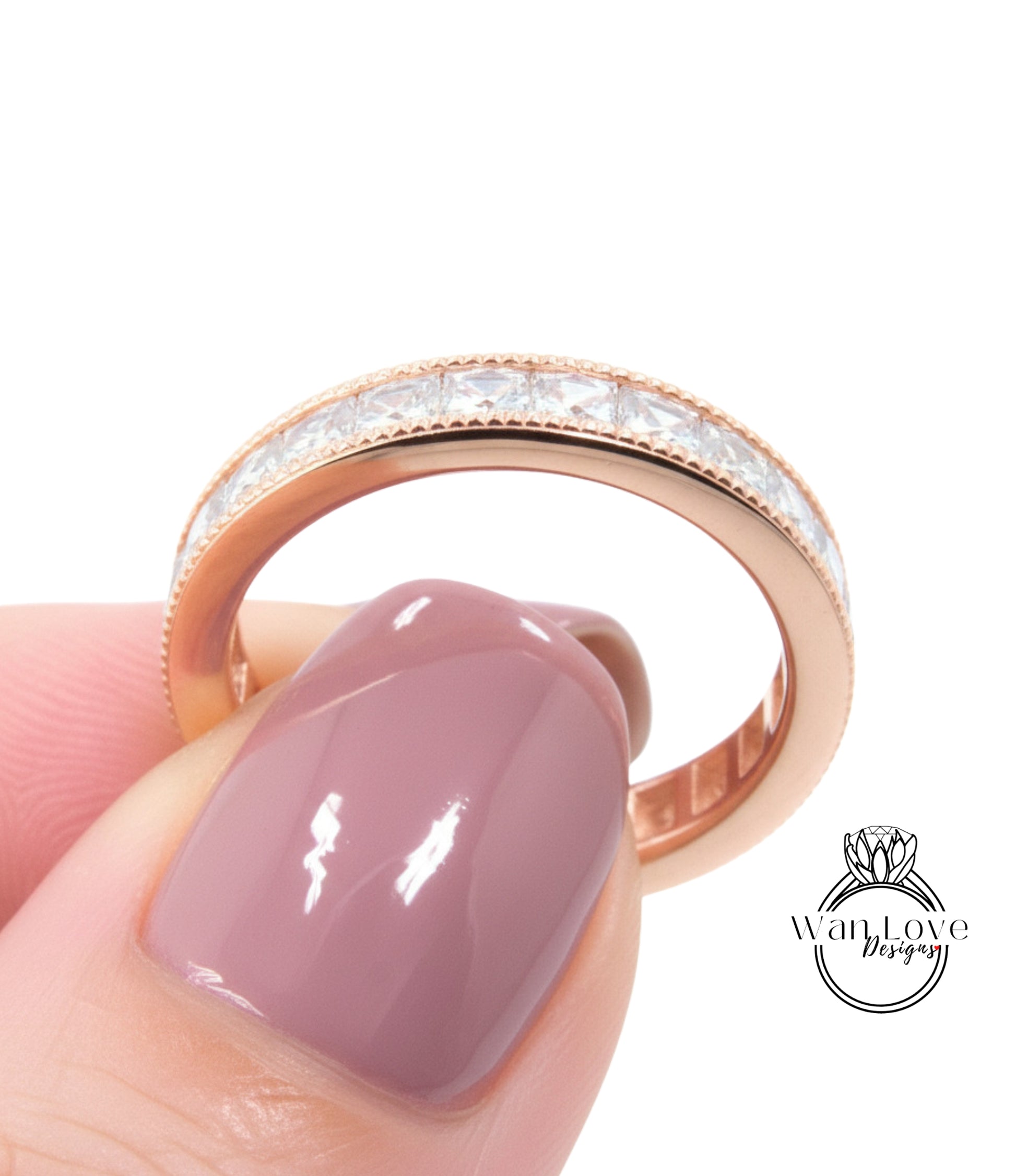 A close-up of a person's hand holding a gold ring with a row of small diamonds along the band.