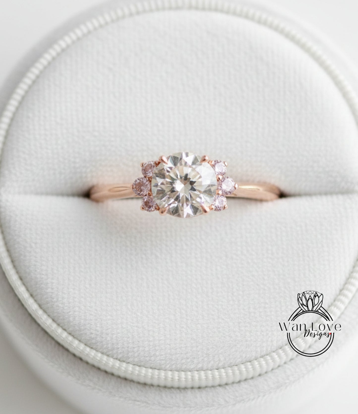 A close-up image of a gold ring with a large diamond set in the center, surrounded by smaller diamonds, displayed in a white jewelry box.