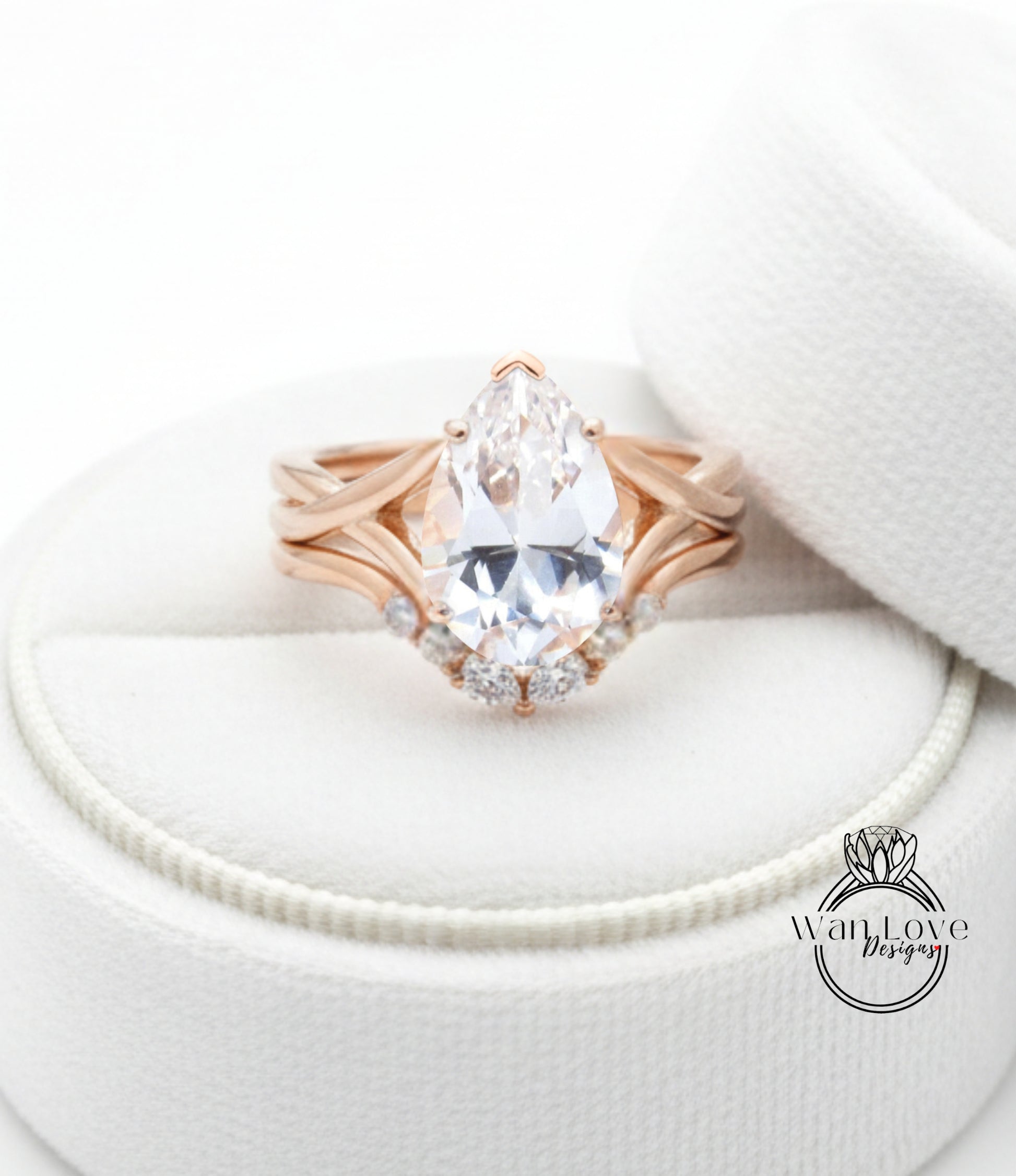 A close-up image of a gold ring with a large pear-shaped diamond set in a ring band, placed on a white fabric background.