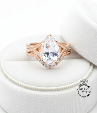 A close-up image of a gold ring with a large pear-shaped diamond set in a ring band, placed on a white fabric background.
