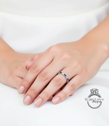 A close-up image of a person's hand wearing a ring with blue gemstones.