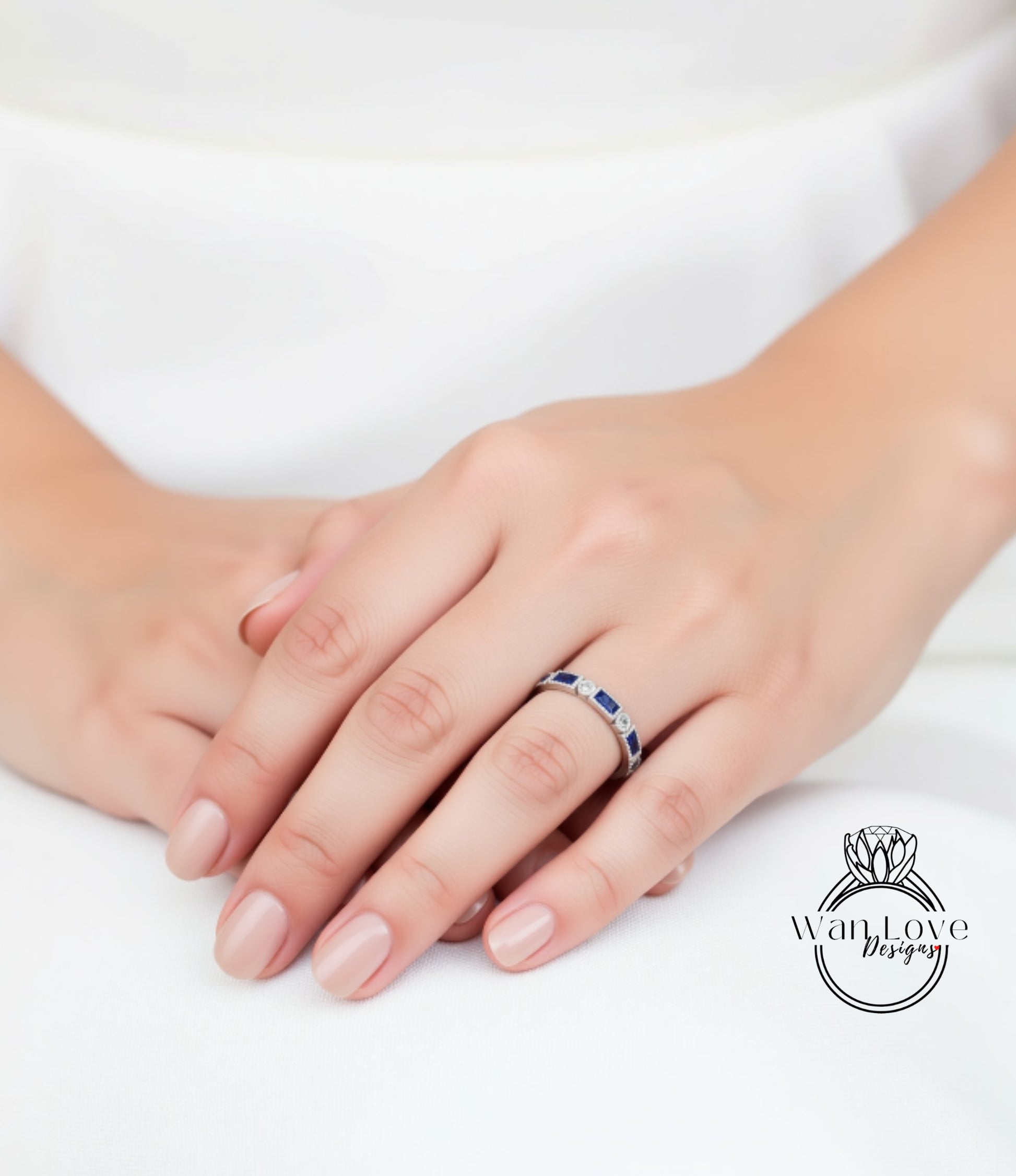 A close-up image of a person's hand wearing a ring with blue gemstones.