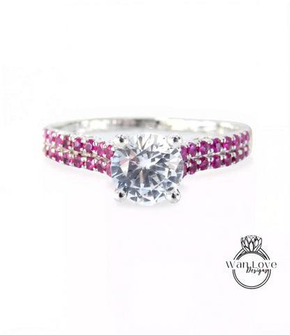 A diamond engagement ring with a large central diamond surrounded by a band of smaller diamonds in shades of pink and white.