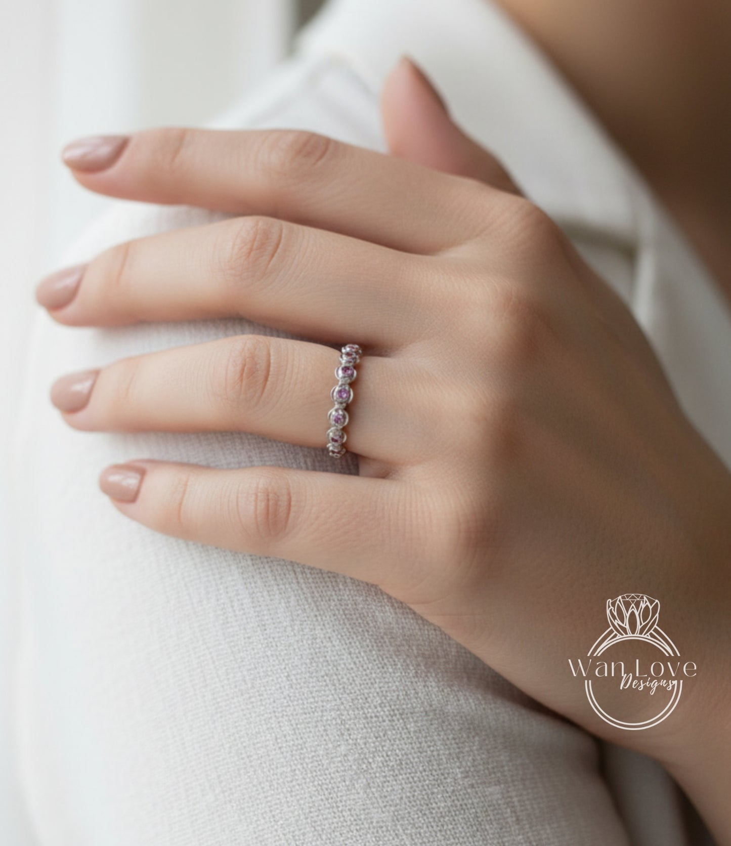 A close-up of a person's hand wearing a ring with a row of small, clear gemstones.
