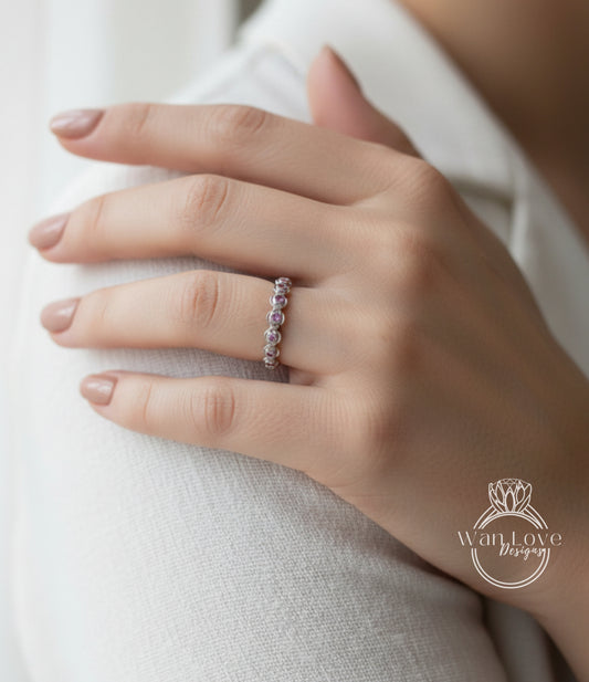 A close-up of a person's hand wearing a ring with a row of small, clear gemstones.