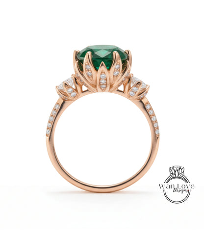 A gold ring with a large green gemstone, surrounded by smaller diamonds, and a flower-like design on the band.