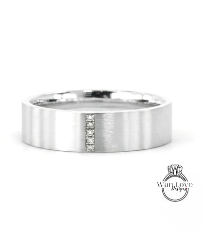 A silver-colored ring with a vertical line and three small diamonds embedded in it.