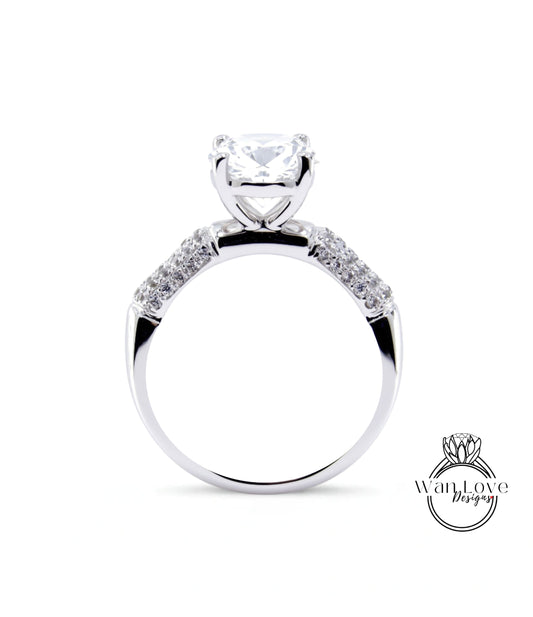 A close-up of a silver engagement ring with a large central diamond and smaller diamonds on either side.