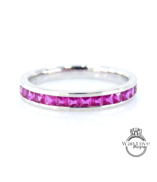 A silver band ring with a row of pink gemstones, likely rubies, set in the center.
