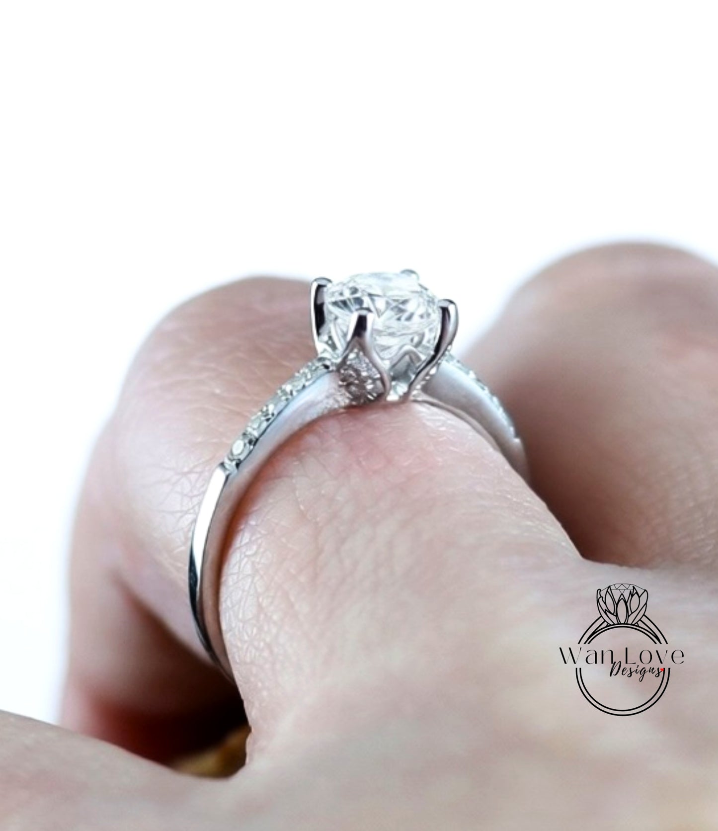 A close-up of a person's hand wearing a diamond engagement ring with a large central diamond surrounded by smaller diamonds on the band.
