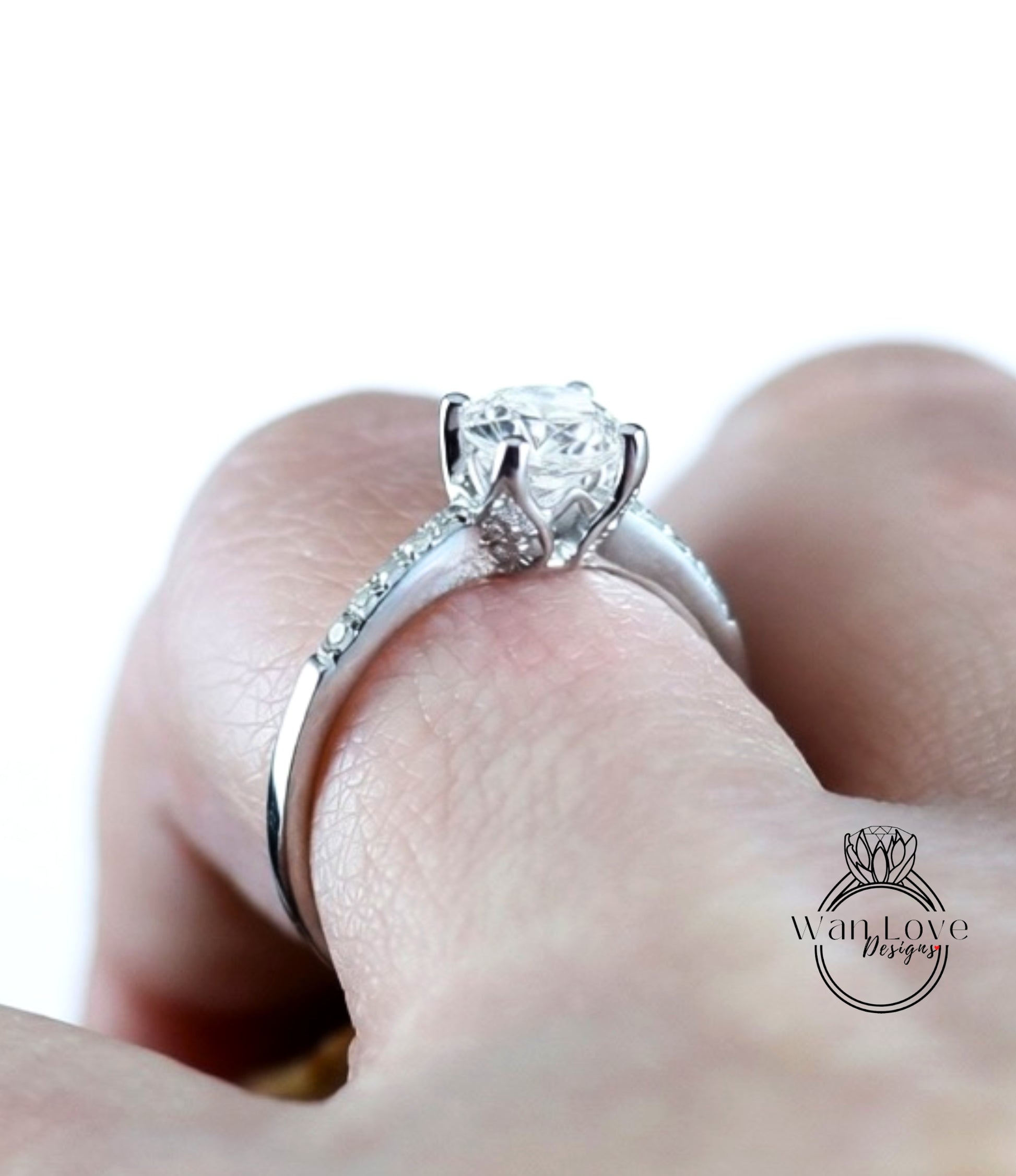 A close-up of a person's hand wearing a diamond engagement ring with a large central diamond surrounded by smaller diamonds on the band.