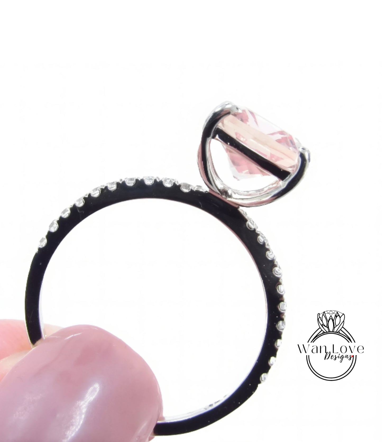 A close-up image of a ring with a large pink gemstone, possibly a diamond, set in a black band with small diamonds.