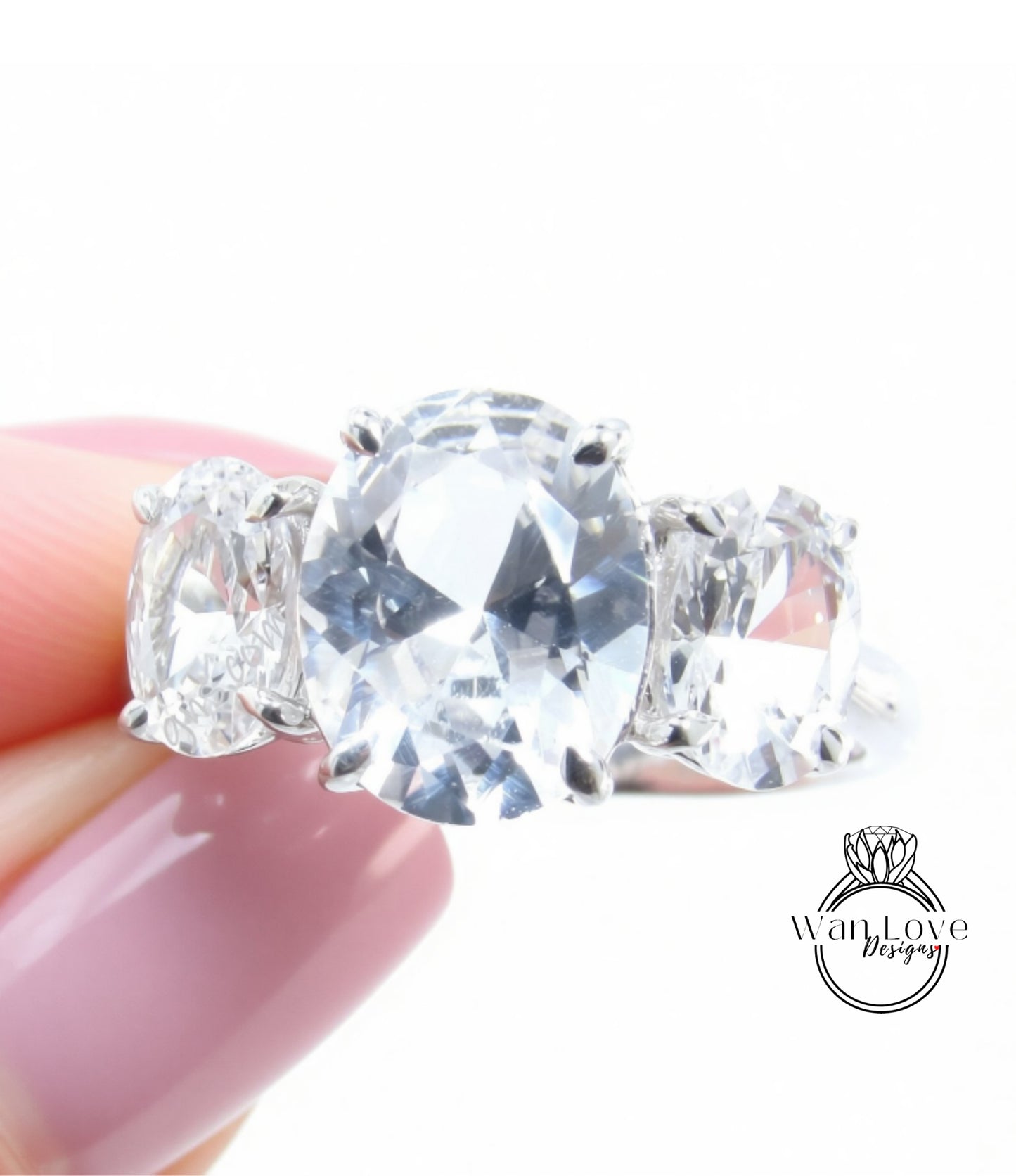A close-up of a person's hand holding a diamond ring with a large oval-shaped gemstone.
