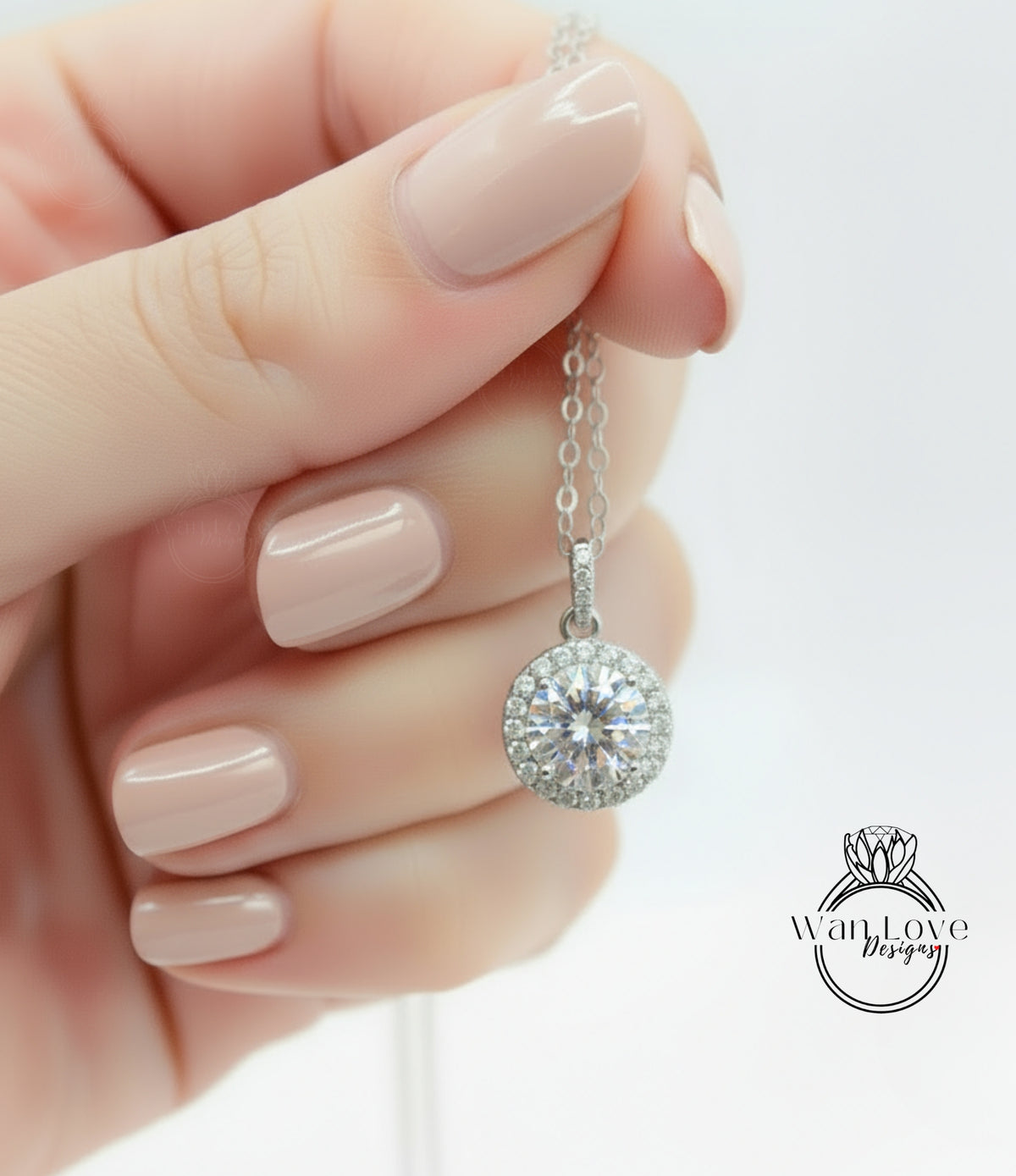 A hand holding a silver necklace with a large, round diamond pendant.